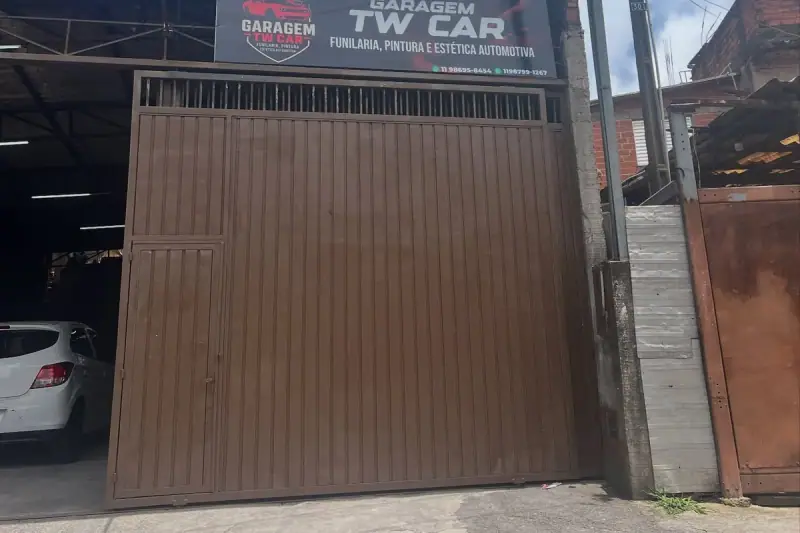 Placa de fachada impressa da Garagem TW Car funilaria e estética automotiva acima de portão metálico