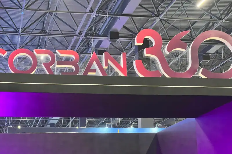 Logo 3D em vermelho do evento Corban 360 instalado sobre a testeira do stand cenográfico