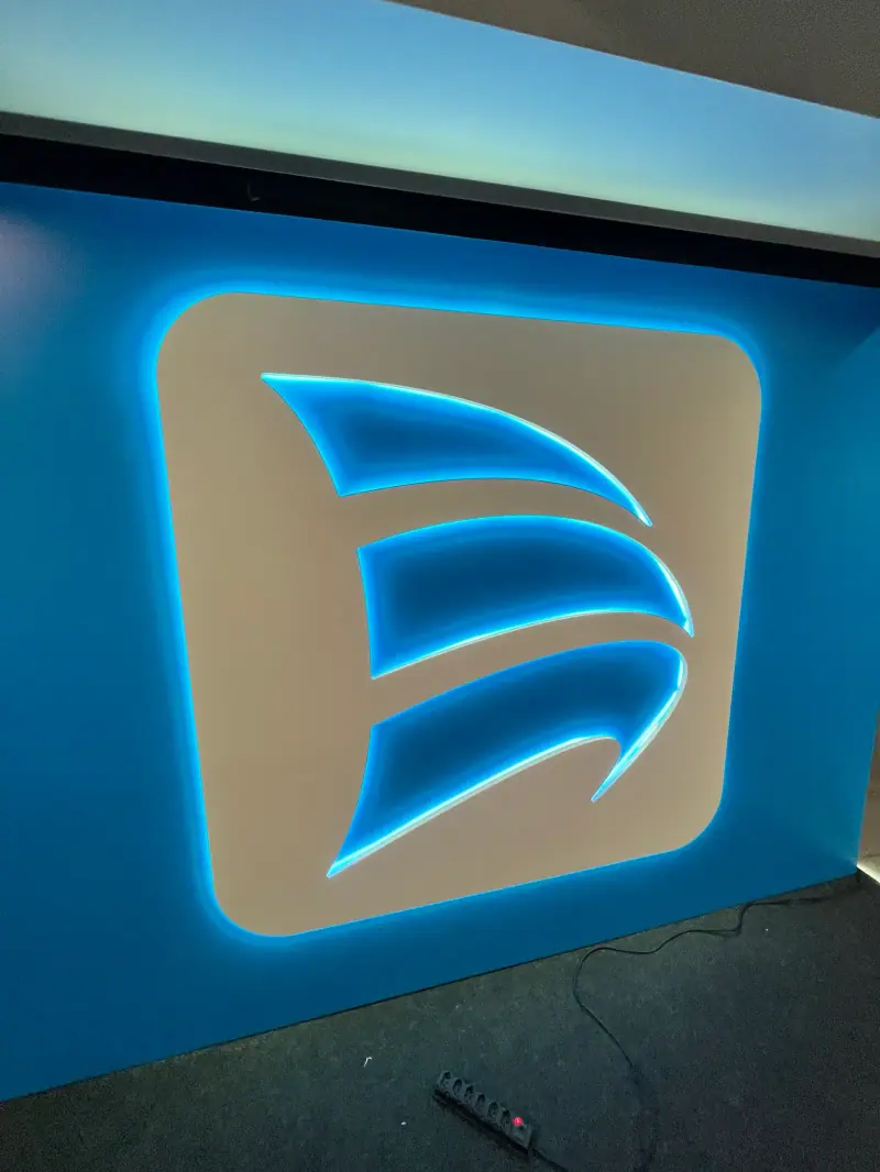 Painel backlight com o símbolo da Porto vazado e iluminação de LED azul em parede de stand