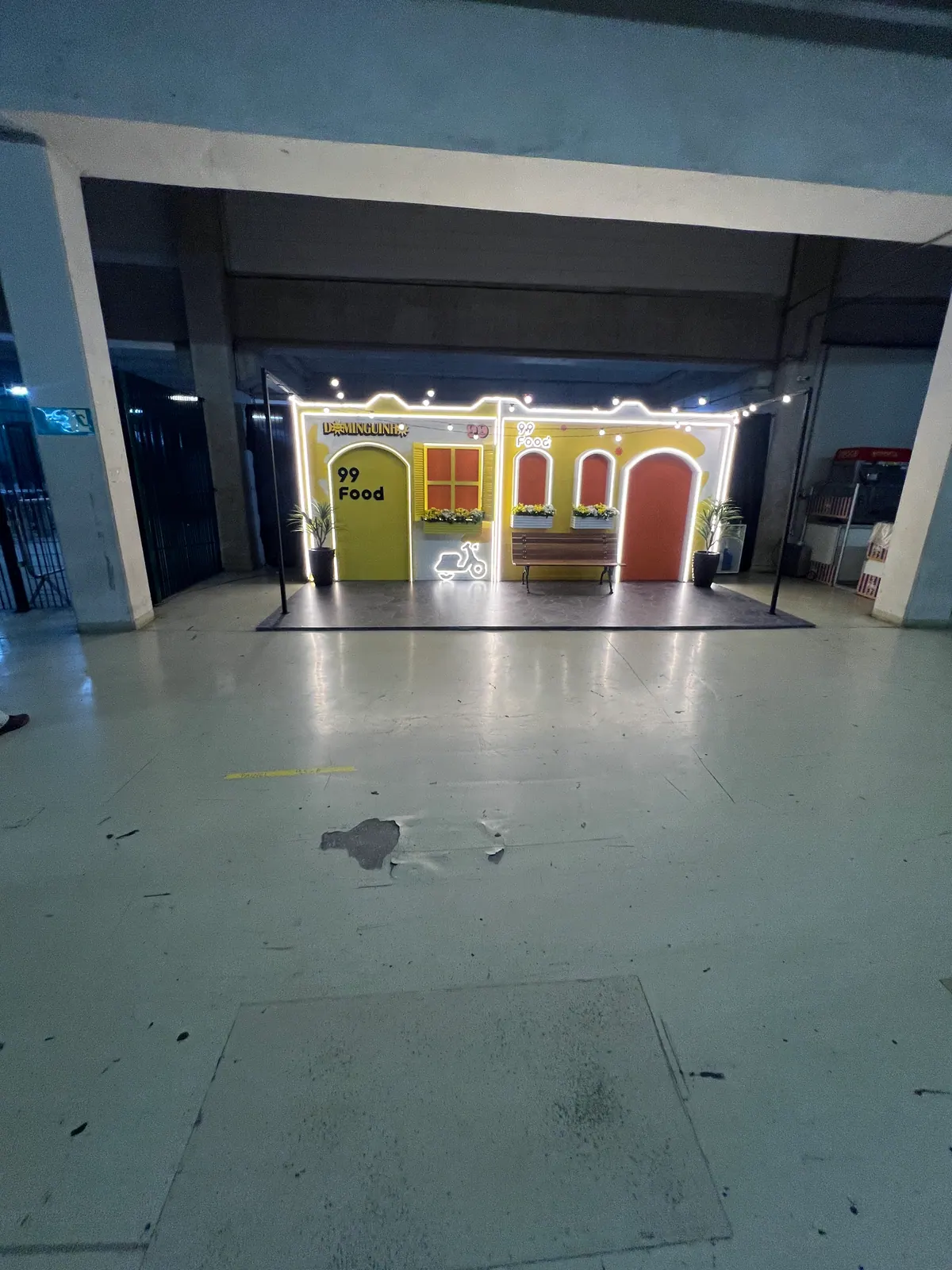 Casinha cenográfica da ativação 99Food com contorno de neon e banco de praça — foto 4