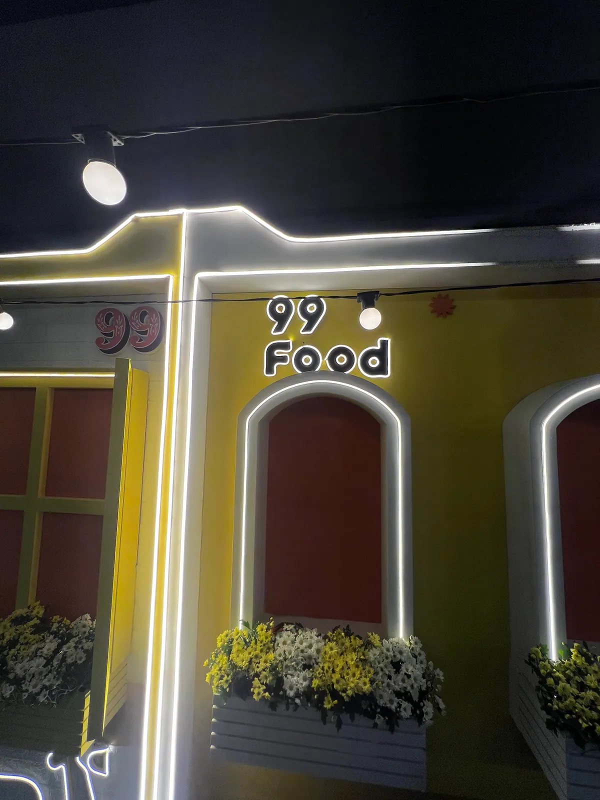 Casinha cenográfica da ativação 99Food com contorno de neon e banco de praça — foto 5