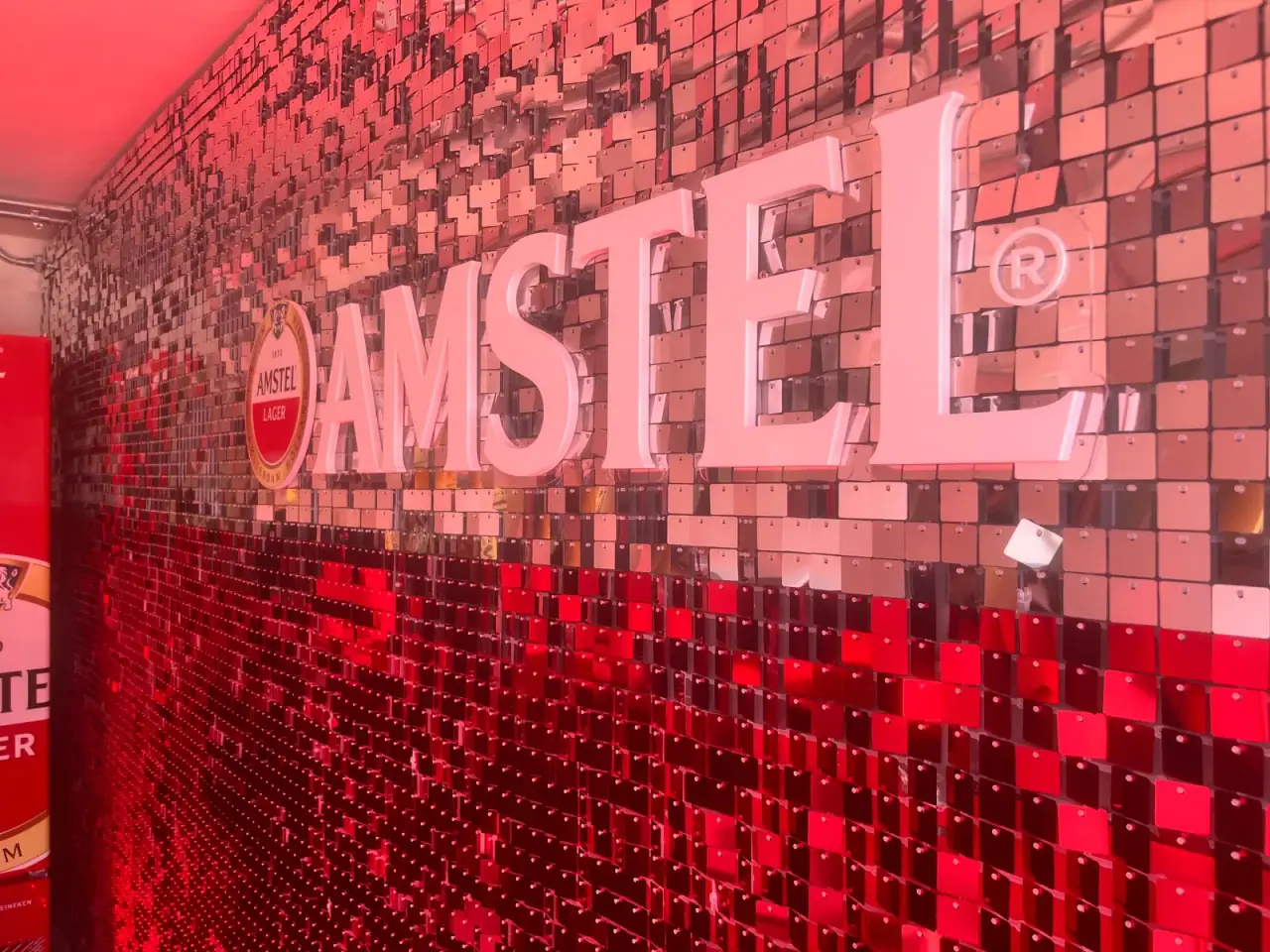 Painel de lantejoulas com logo da Amstel e letreiros iluminados em evento — foto 1