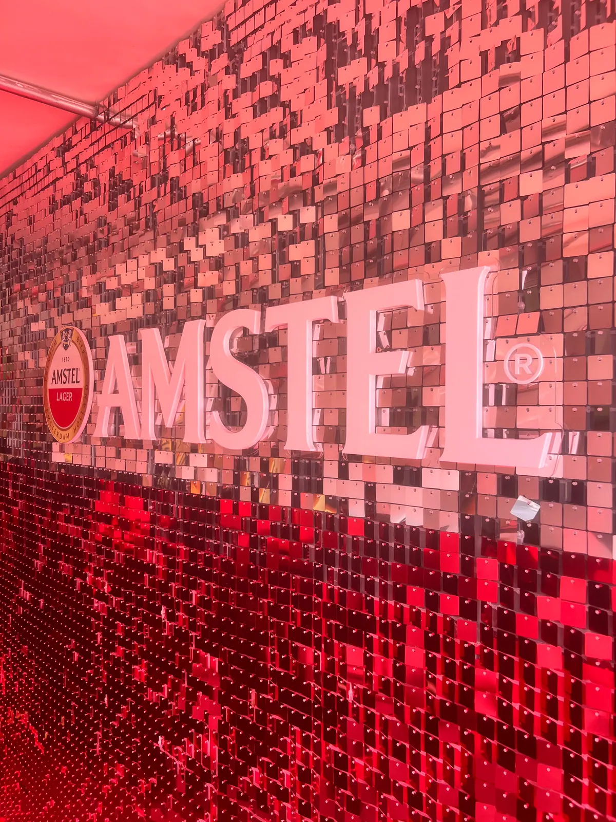Painel de lantejoulas com logo da Amstel e letreiros iluminados em evento — foto 2