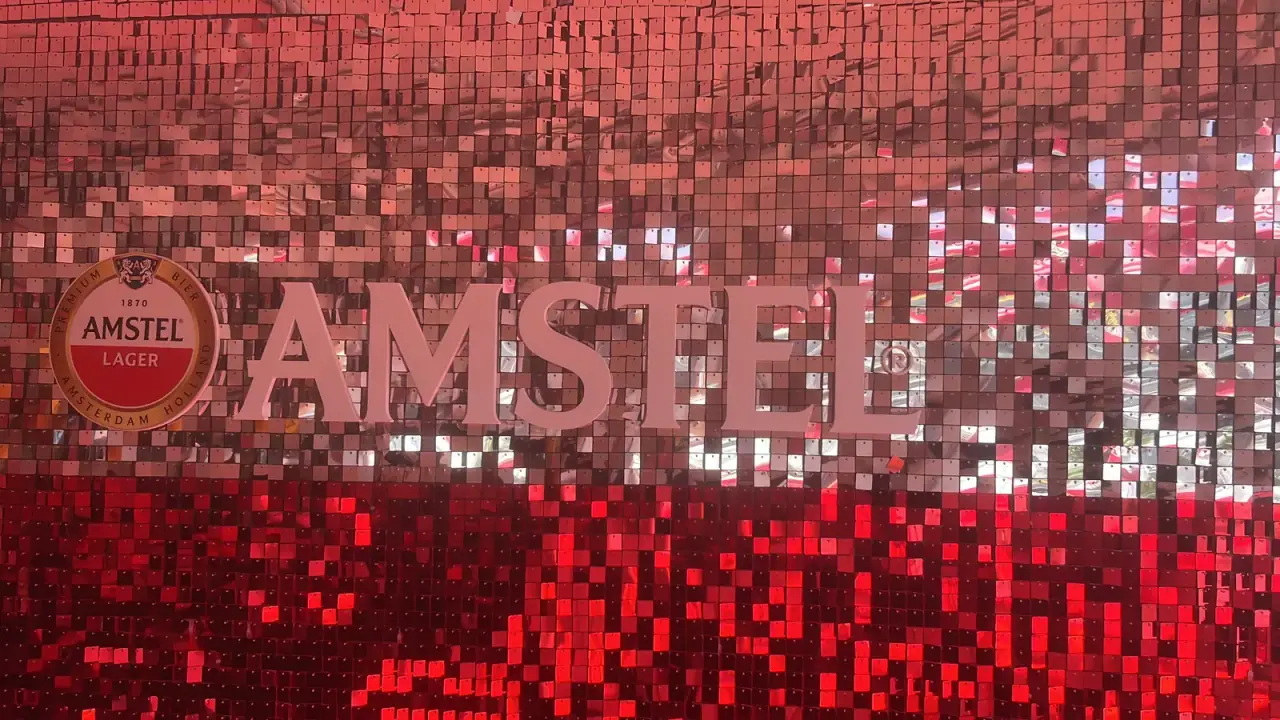 Painel de lantejoulas com logo da Amstel e letreiros iluminados em evento — foto 3