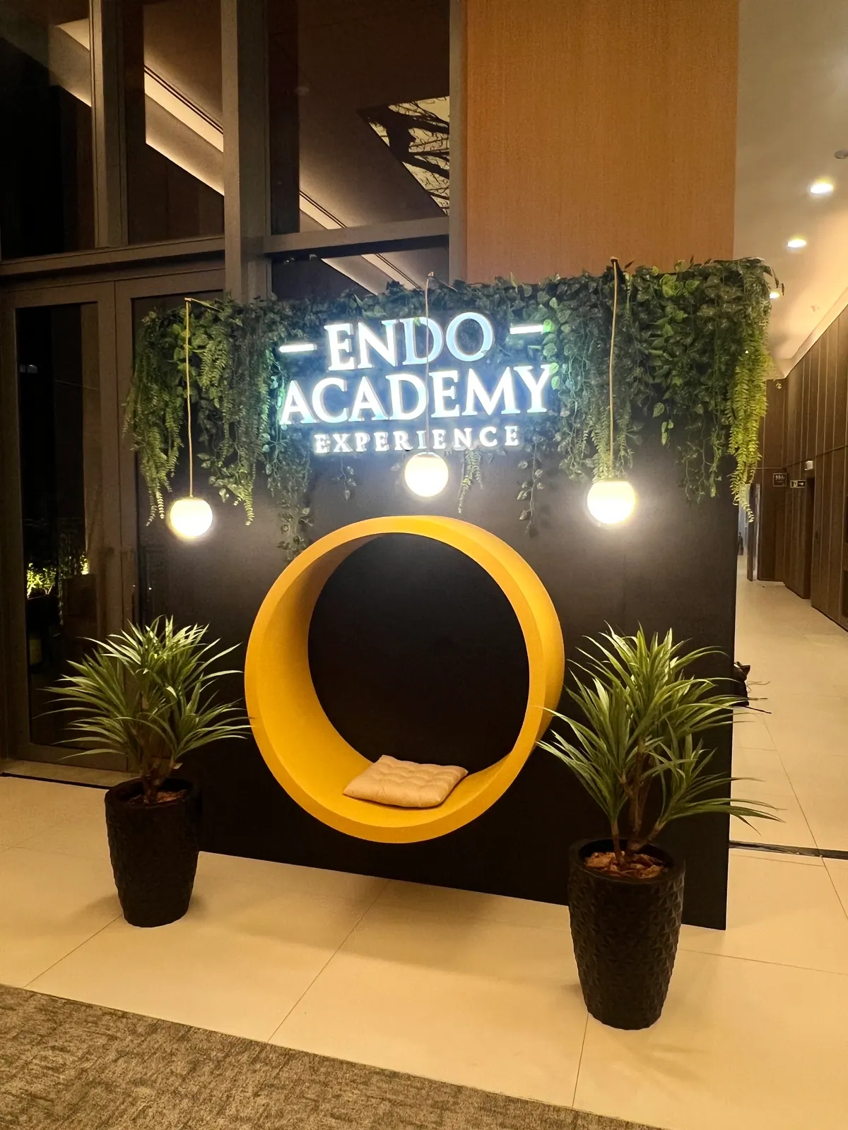 Painel cenográfico da Endo Academy Experience com letreiro iluminado e jardim — foto 1
