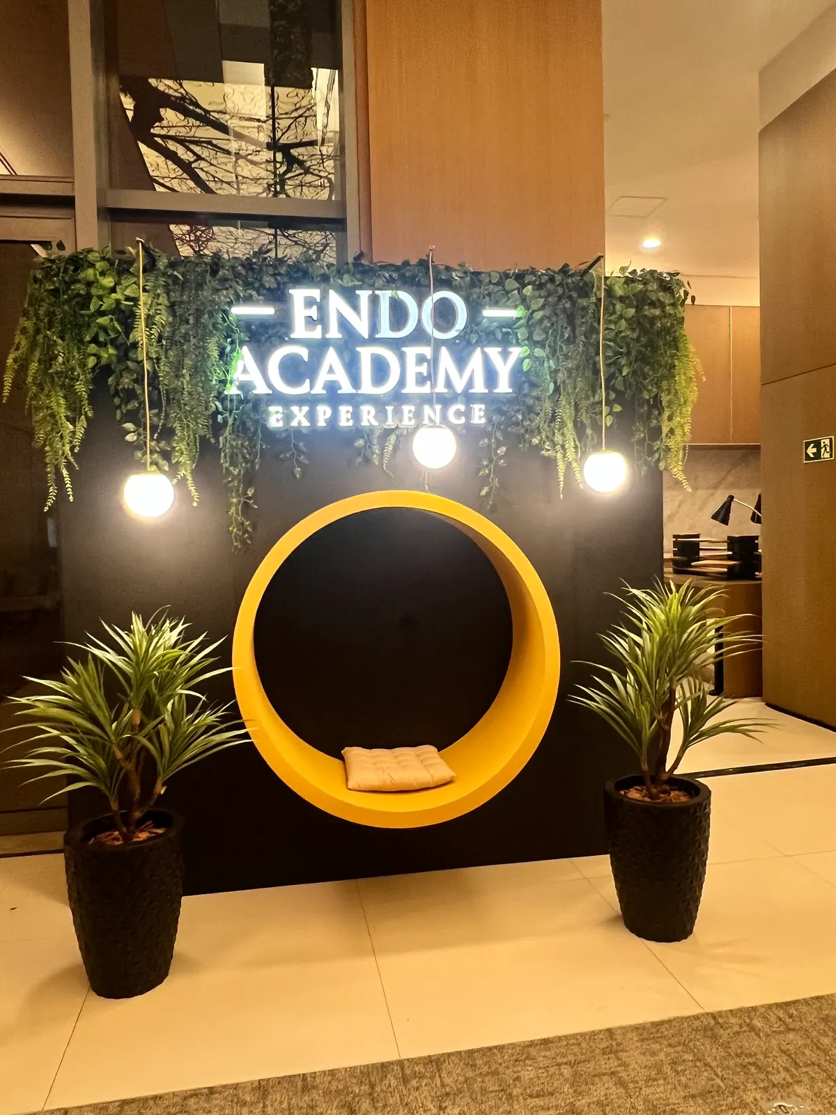 Painel cenográfico da Endo Academy Experience com letreiro iluminado e jardim — foto 2