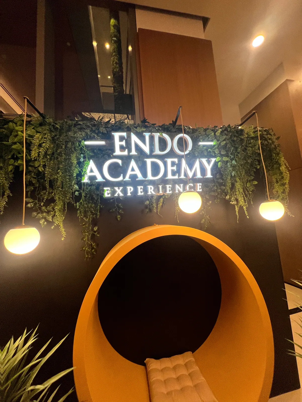 Painel cenográfico da Endo Academy Experience com letreiro iluminado e jardim — foto 3