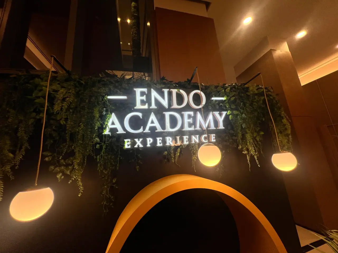 Painel cenográfico da Endo Academy Experience com letreiro iluminado e jardim — foto 4