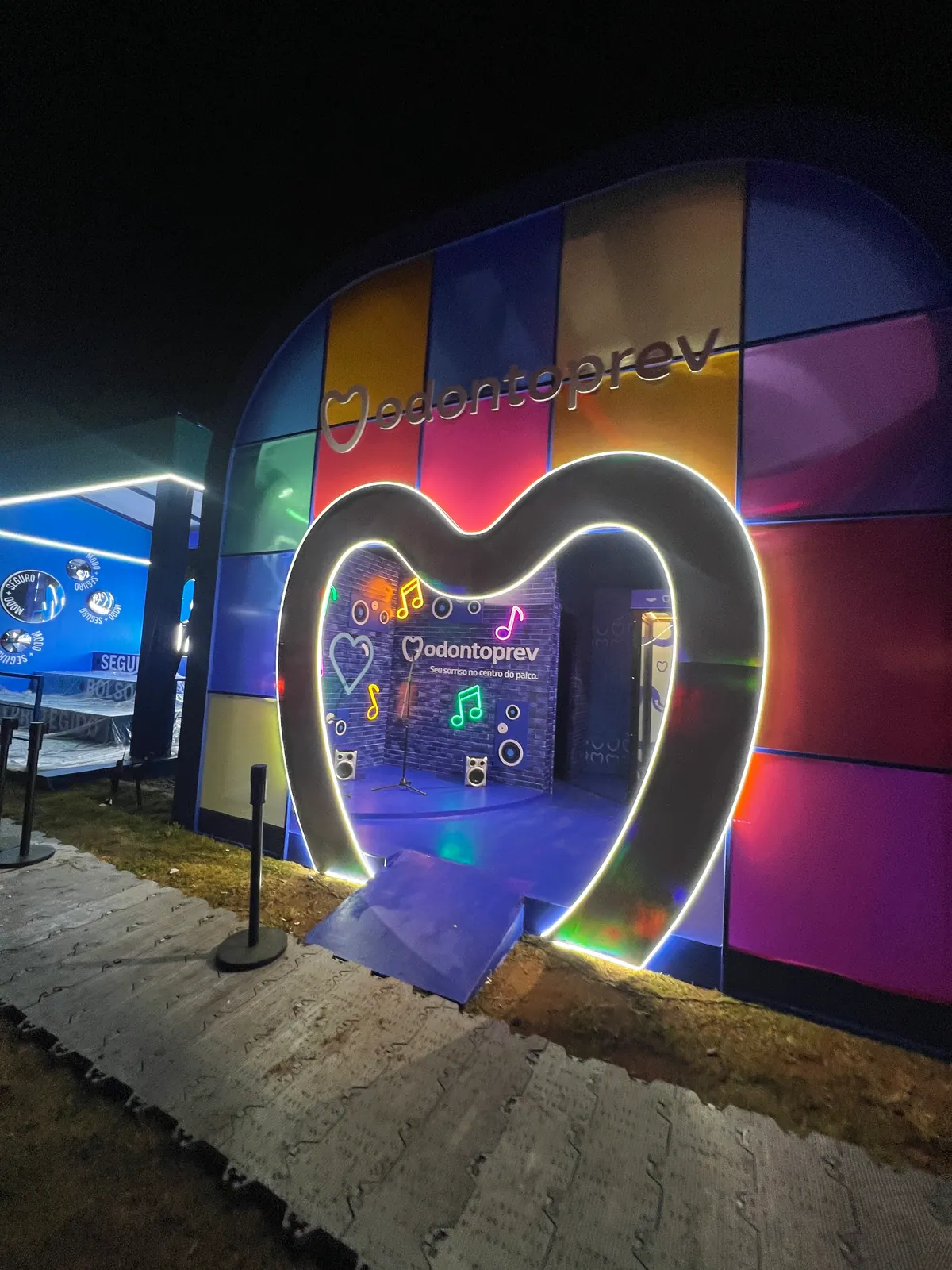 Espaço da Odontoprev em festival com entrada em coração iluminado e cenário de neon — foto 2