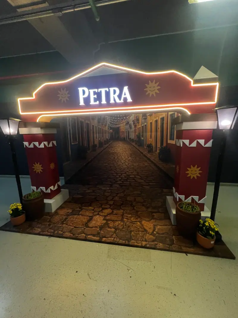 Ativação cenográfica da Petra em festival, com portal temático, bar e letreiros iluminados — foto 1