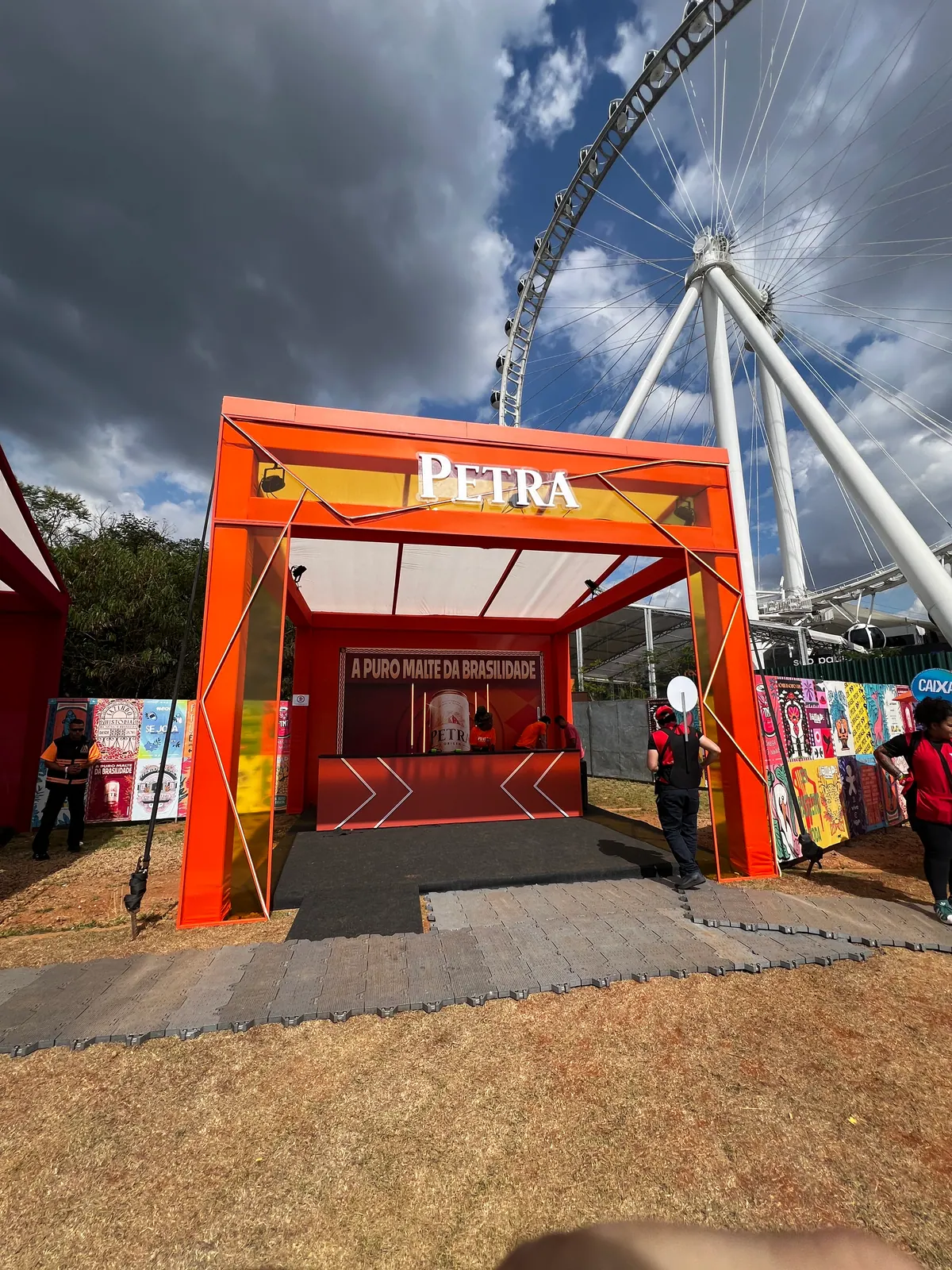 Ativação cenográfica da Petra em festival, com portal temático, bar e letreiros iluminados — foto 2