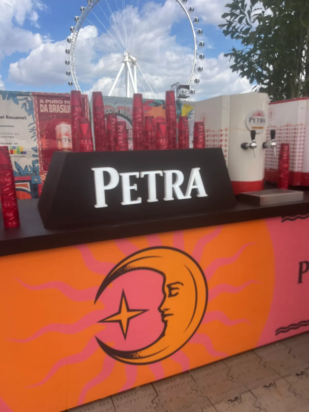 Ativação cenográfica da Petra em festival, com portal temático, bar e letreiros iluminados — foto 4