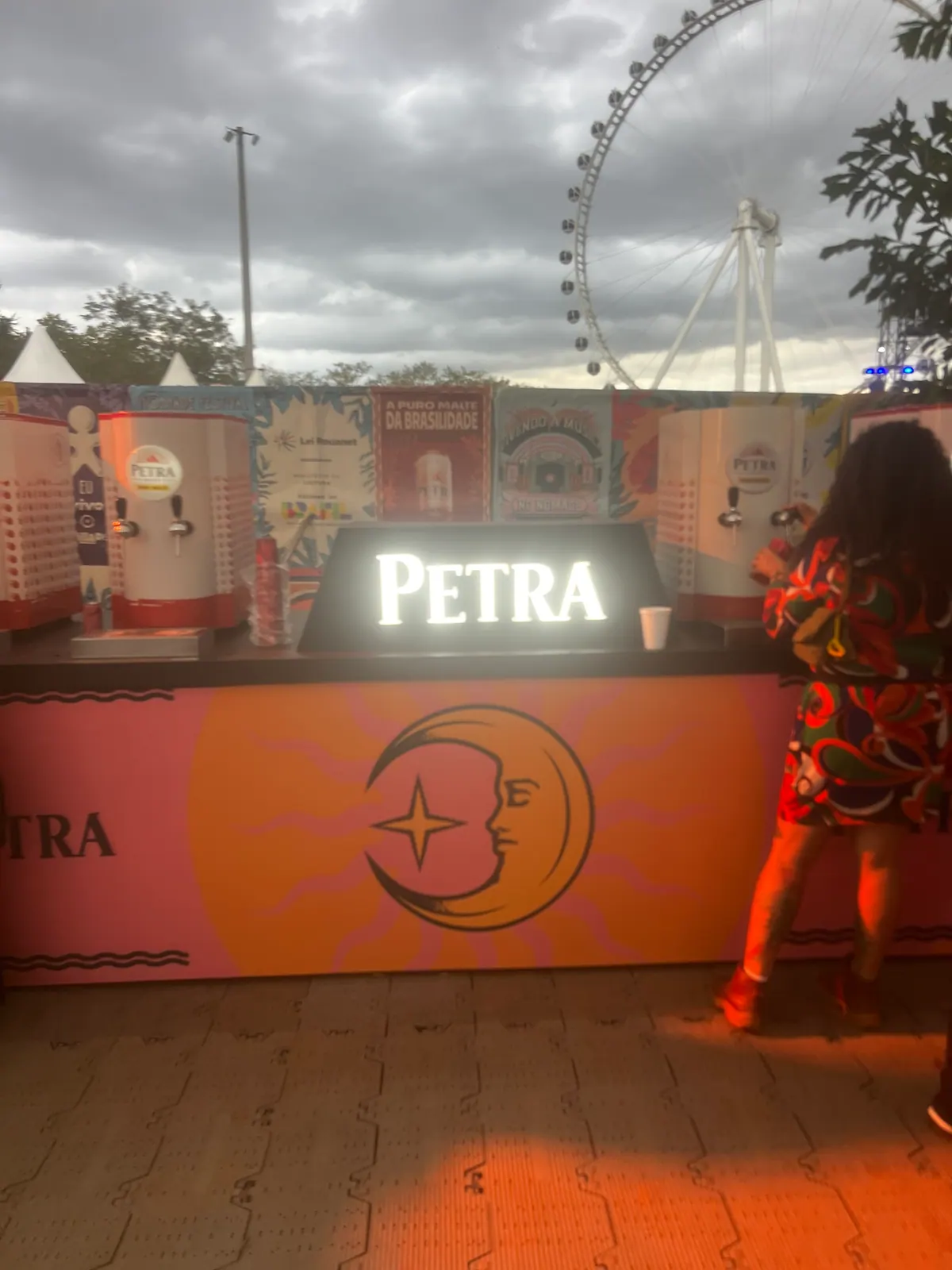 Ativação cenográfica da Petra em festival, com portal temático, bar e letreiros iluminados — foto 7
