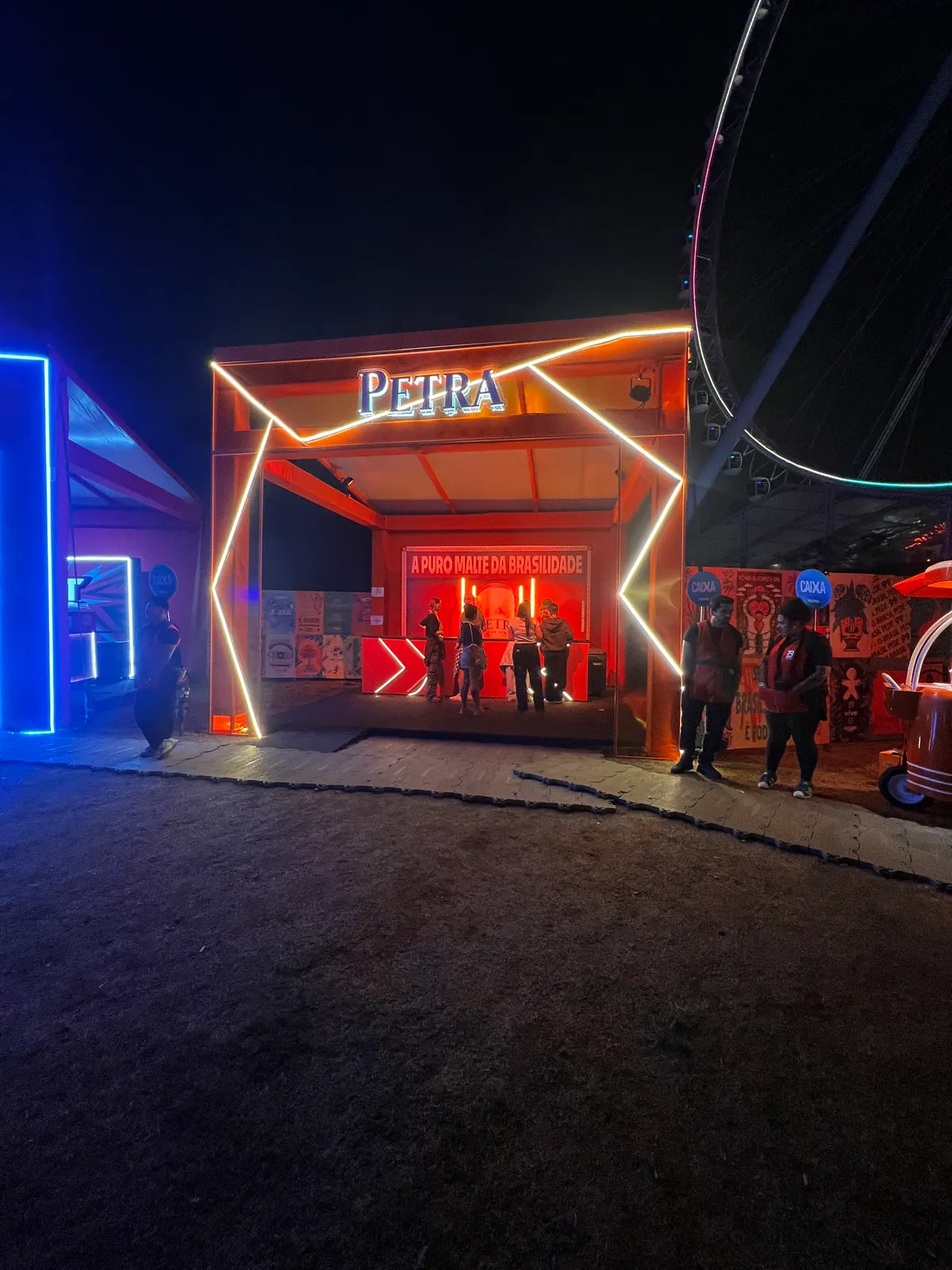 Ativação cenográfica da Petra em festival, com portal temático, bar e letreiros iluminados — foto 9