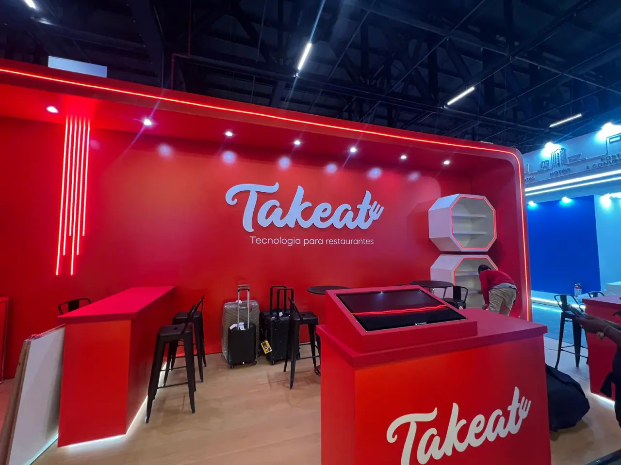 Stand da Takeat com logo em relevo sobre painel vermelho — foto 1