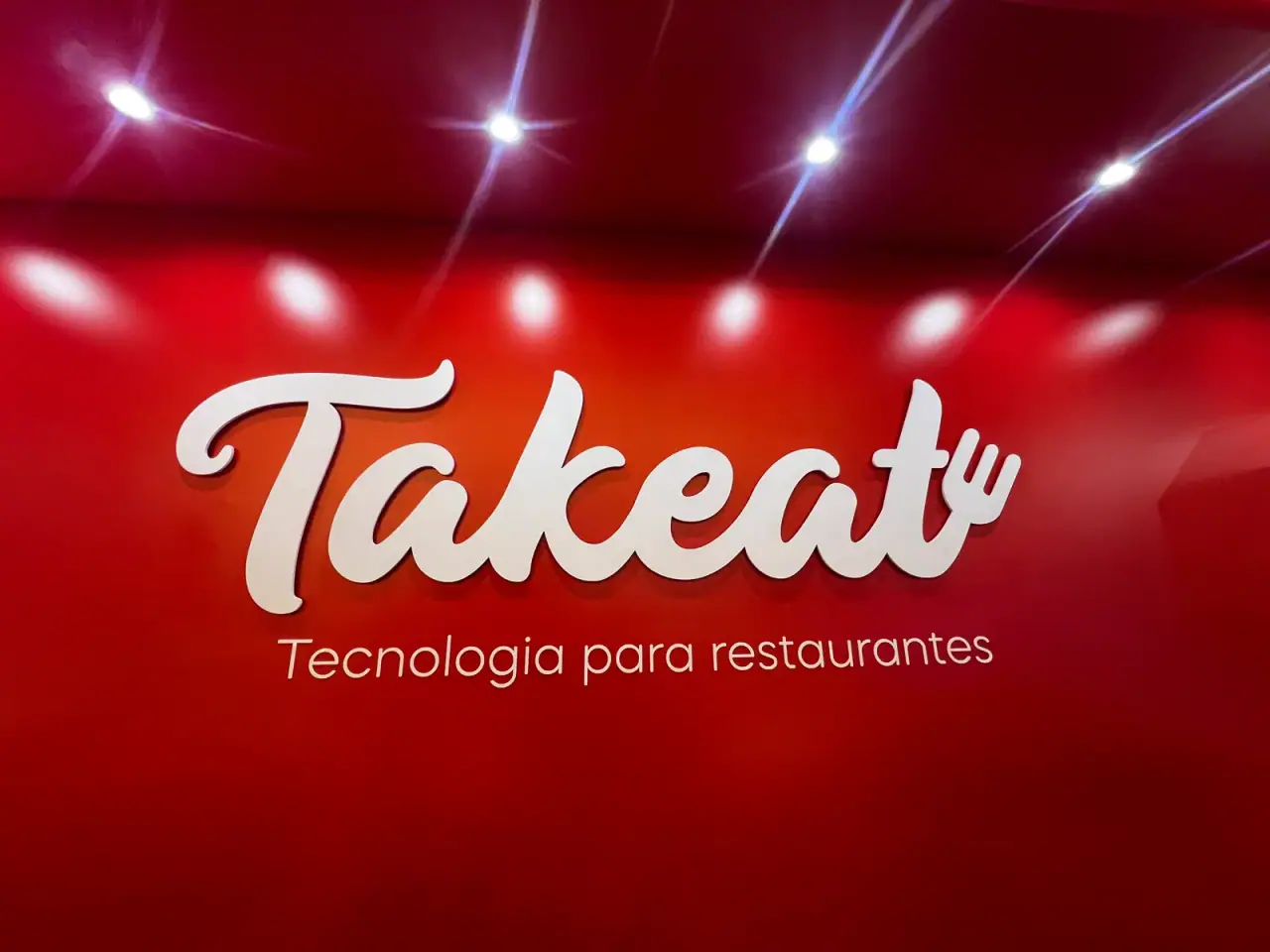 Stand da Takeat com logo em relevo sobre painel vermelho — foto 4