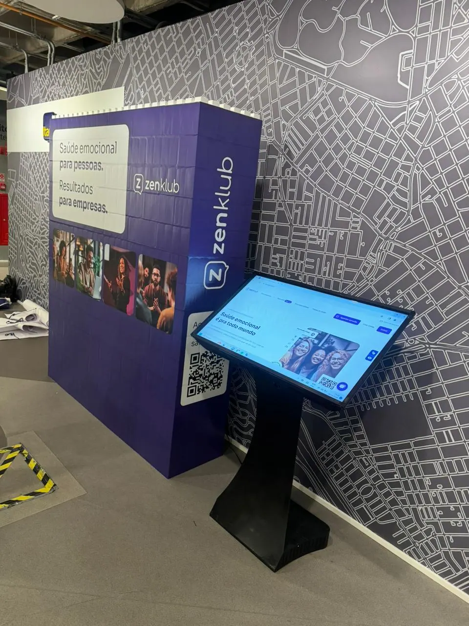 Stand da Zenklub com totem digital e painel gráfico